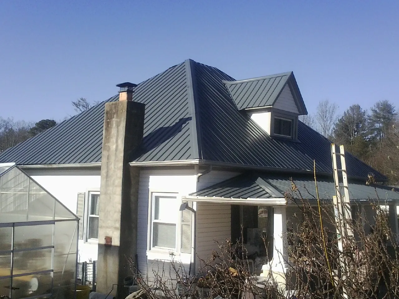 Dark blue standing seam metal roof on a white farmhouse with dormer — Slate & Tile Roof Repair by Roofing Brothers in Claryville