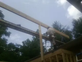 Carpenter setting a ridge beam over a new addition frame — Ice Dam Removal by Roofing Brothers in Claryville