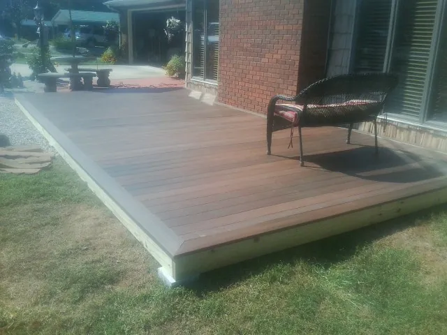 New wood deck and wicker chair beside a brick house in Claryville
