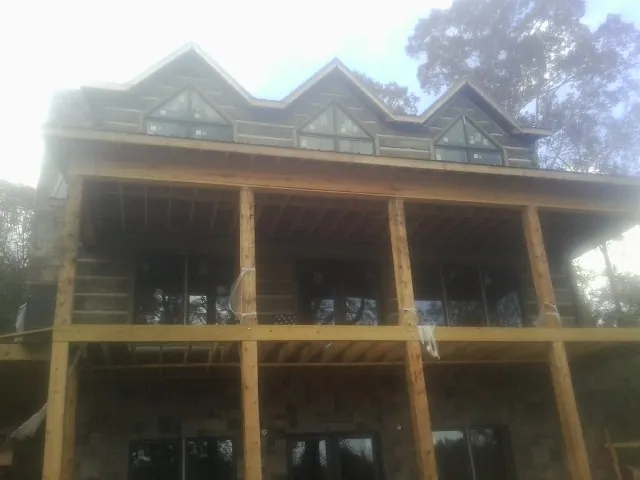 Dormers and porch framing on a large log home under construction — Roof Coating work by our crew in Claryville