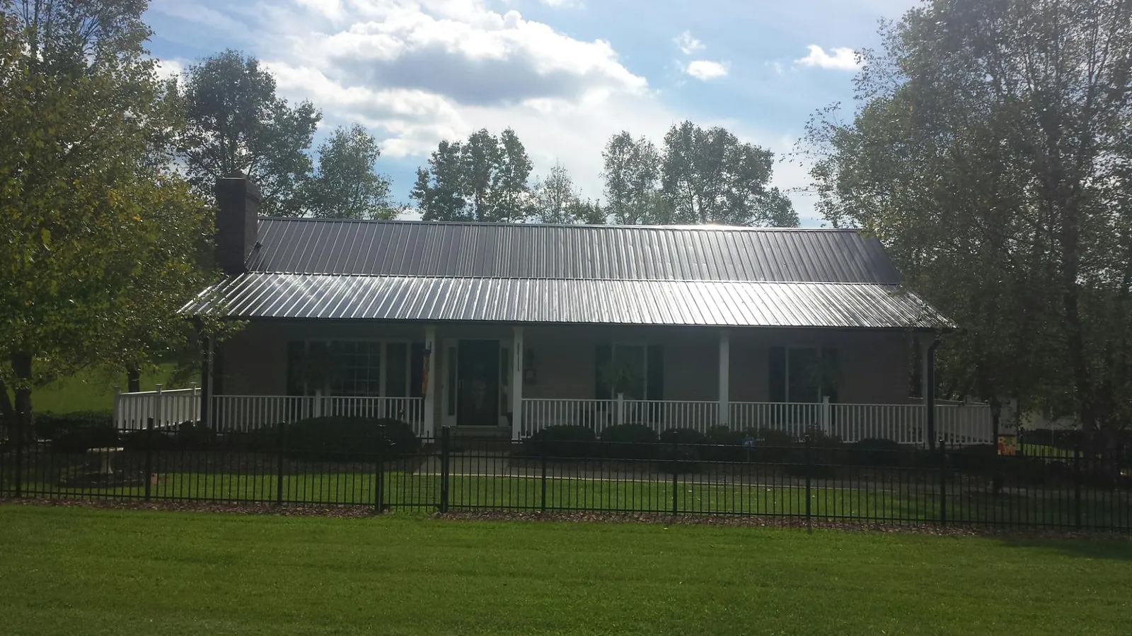 Gray metal roof on a brick ranch with a full width front porch — Gutter Guard Installation work by our crew in Claryville