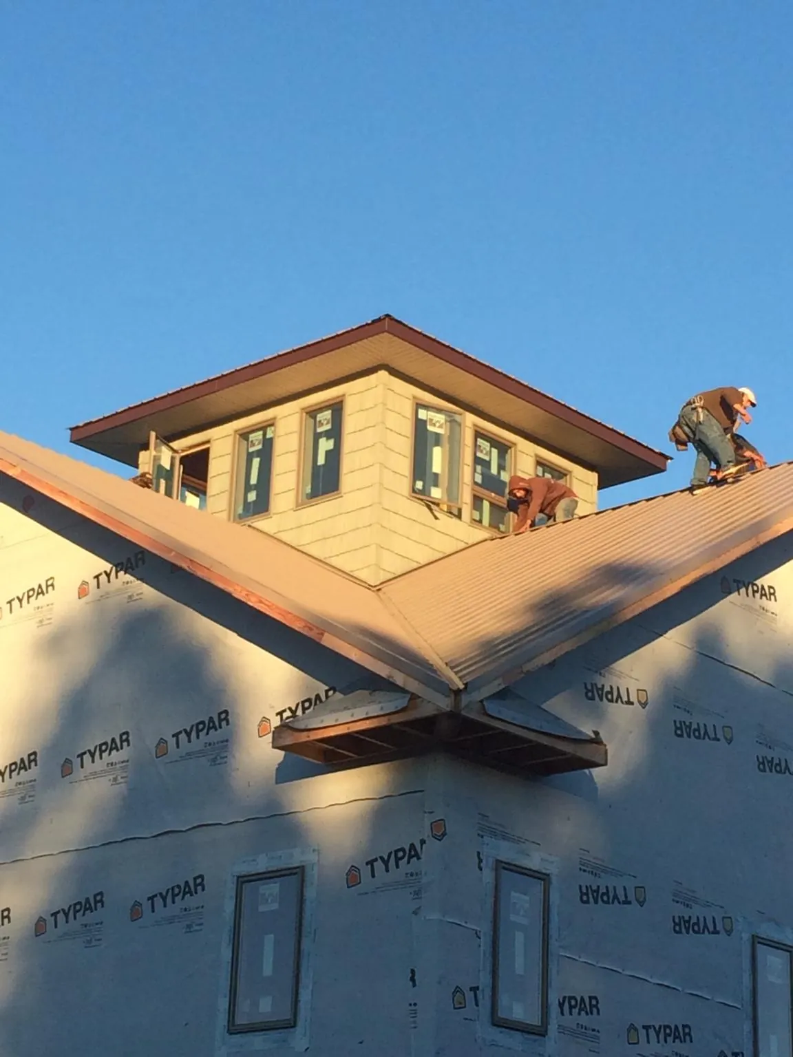 Roofers working around a rooftop cupola on a new metal roof at sunset — Roof Waterproofing in Claryville by Roofing Brothers